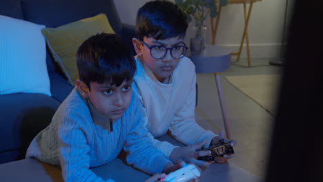 Two-Young-Boys-At-Home-Playing-With-Computer-Games-Console-On-TV-Holding-Controllers-Late-At-Night-2